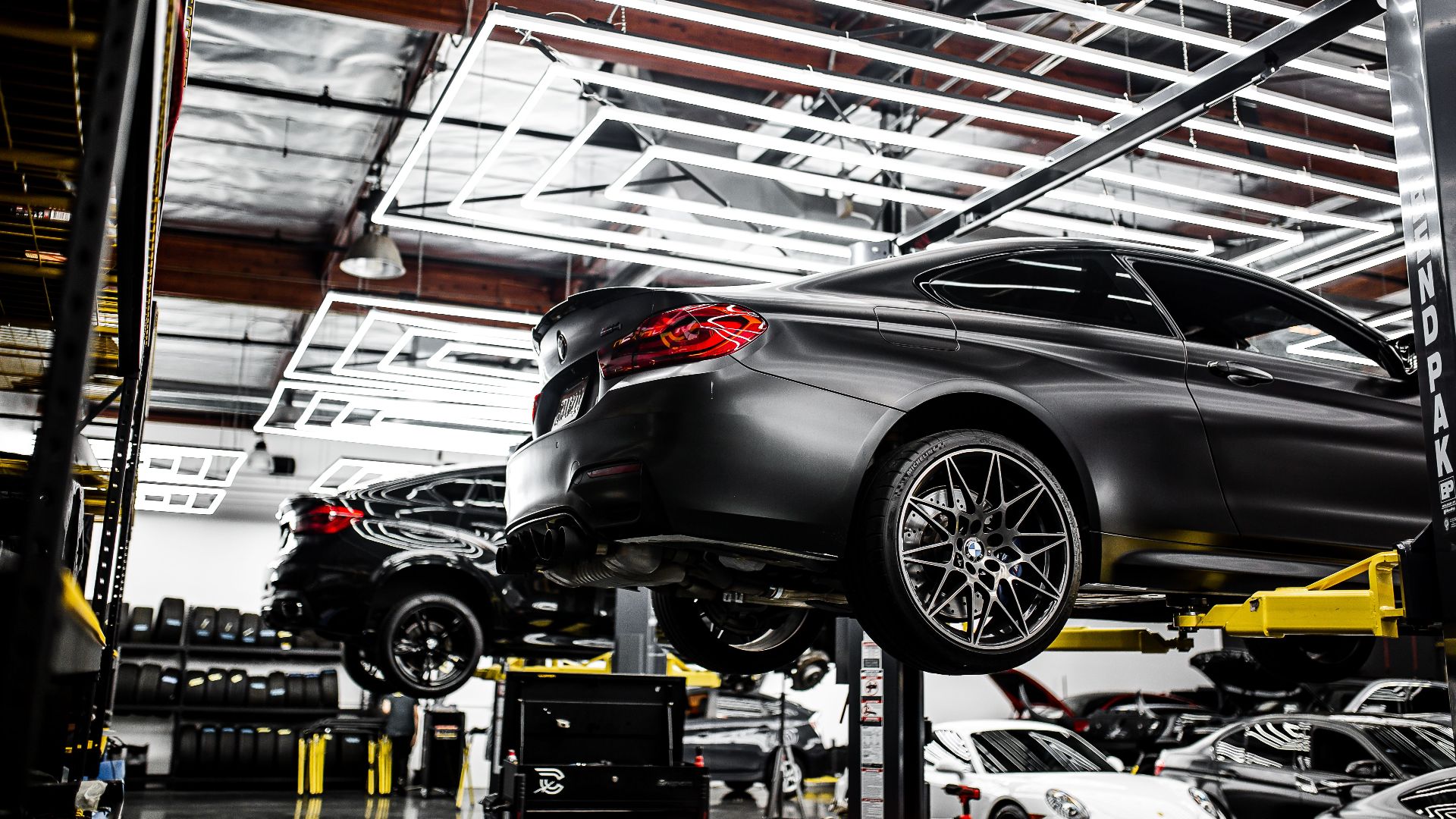A modern car repair shop showcasing vehicles on lifts and a well-lit, organized interior.