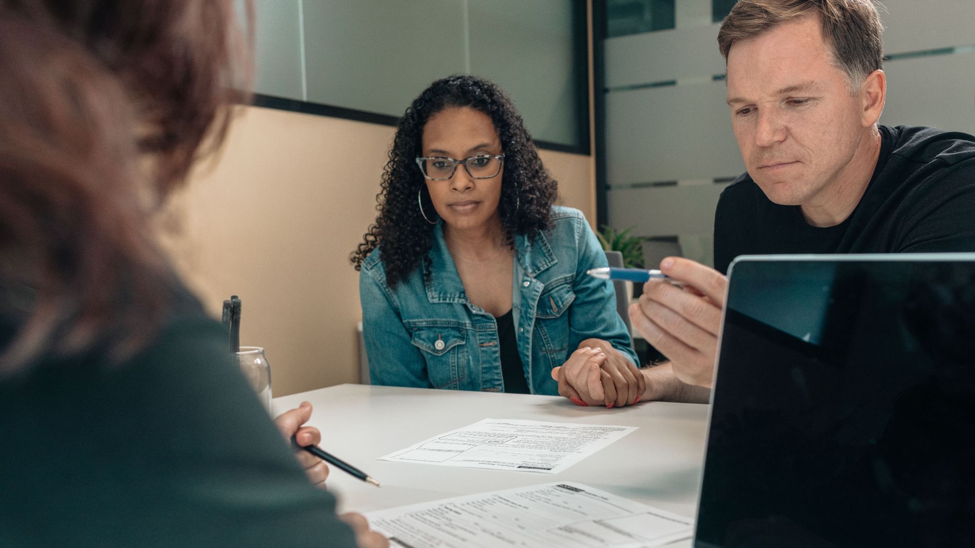 A couple reviewing documents with a professional in an office setting, focusing on financial planning.