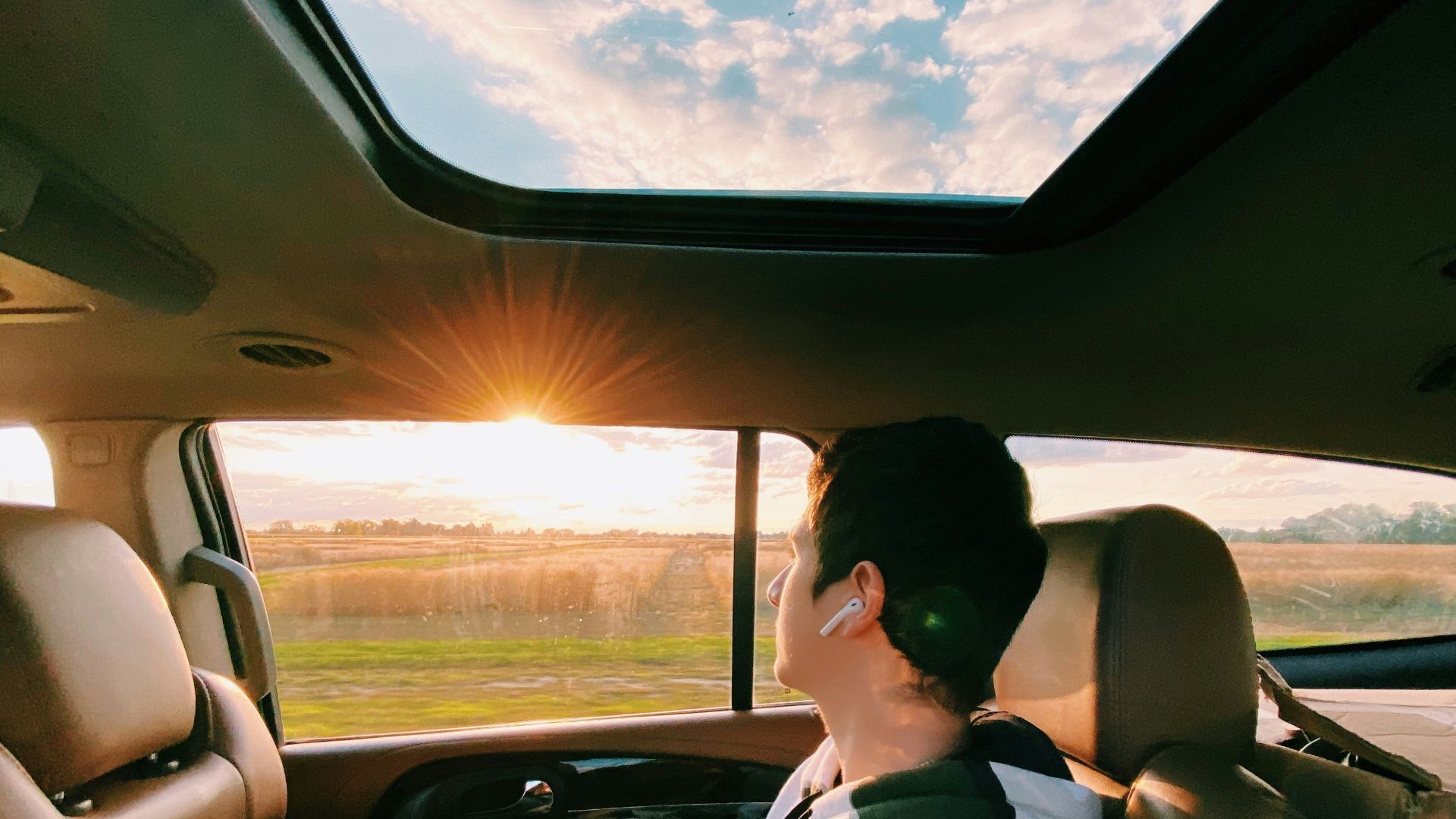 woman in white and black floral shirt driving car during daytime