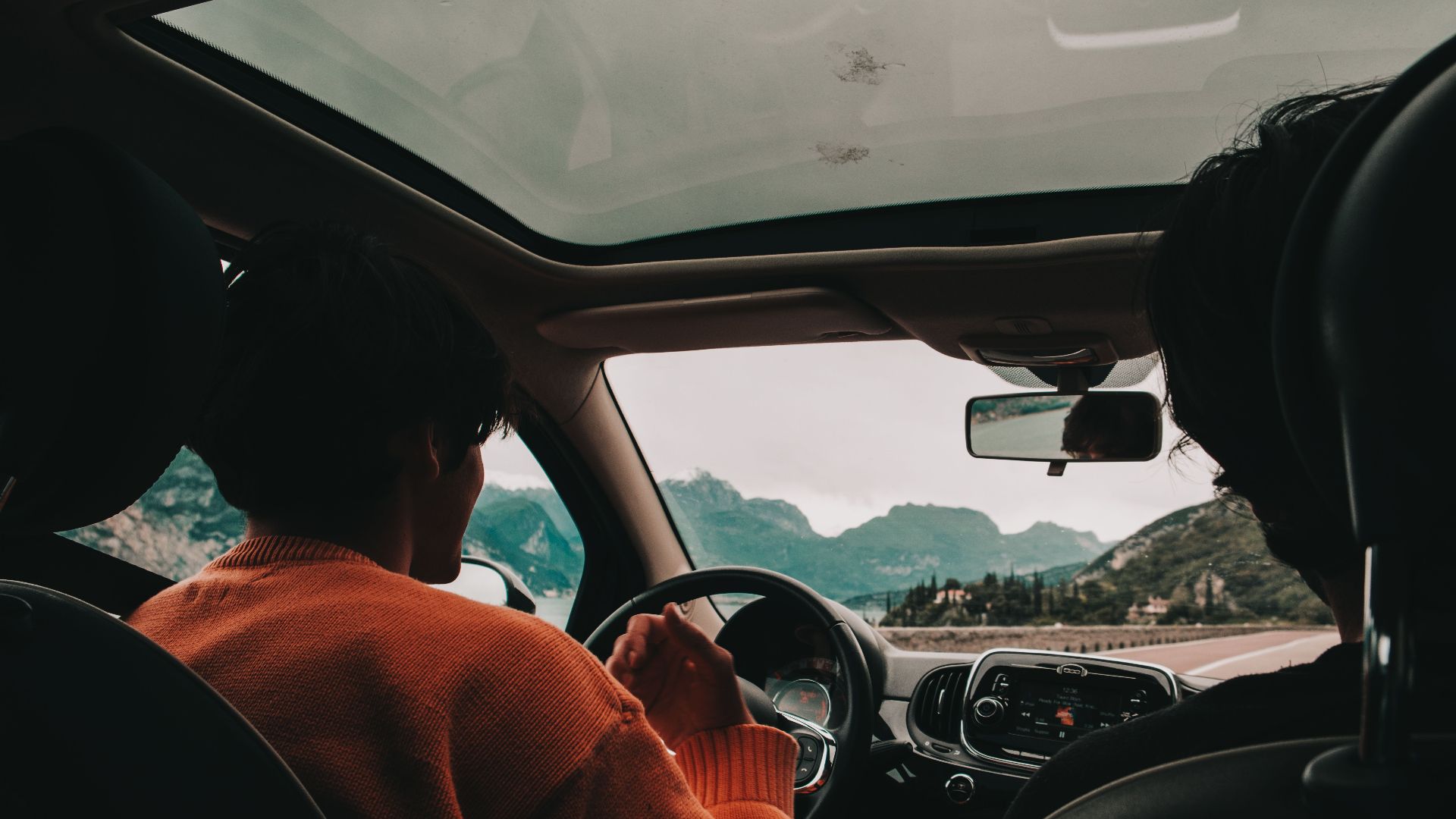 Enjoy a scenic drive through mountains with friends. Front passenger view from inside the car.