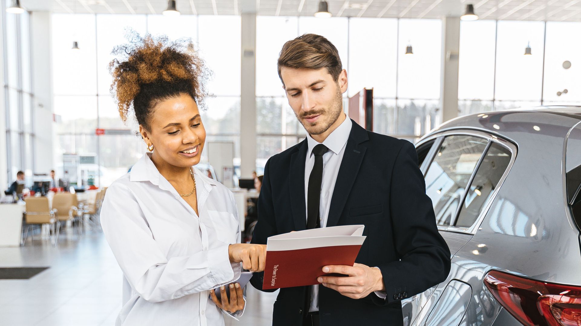Man and woman discussing car purchase inside a modern dealership.
