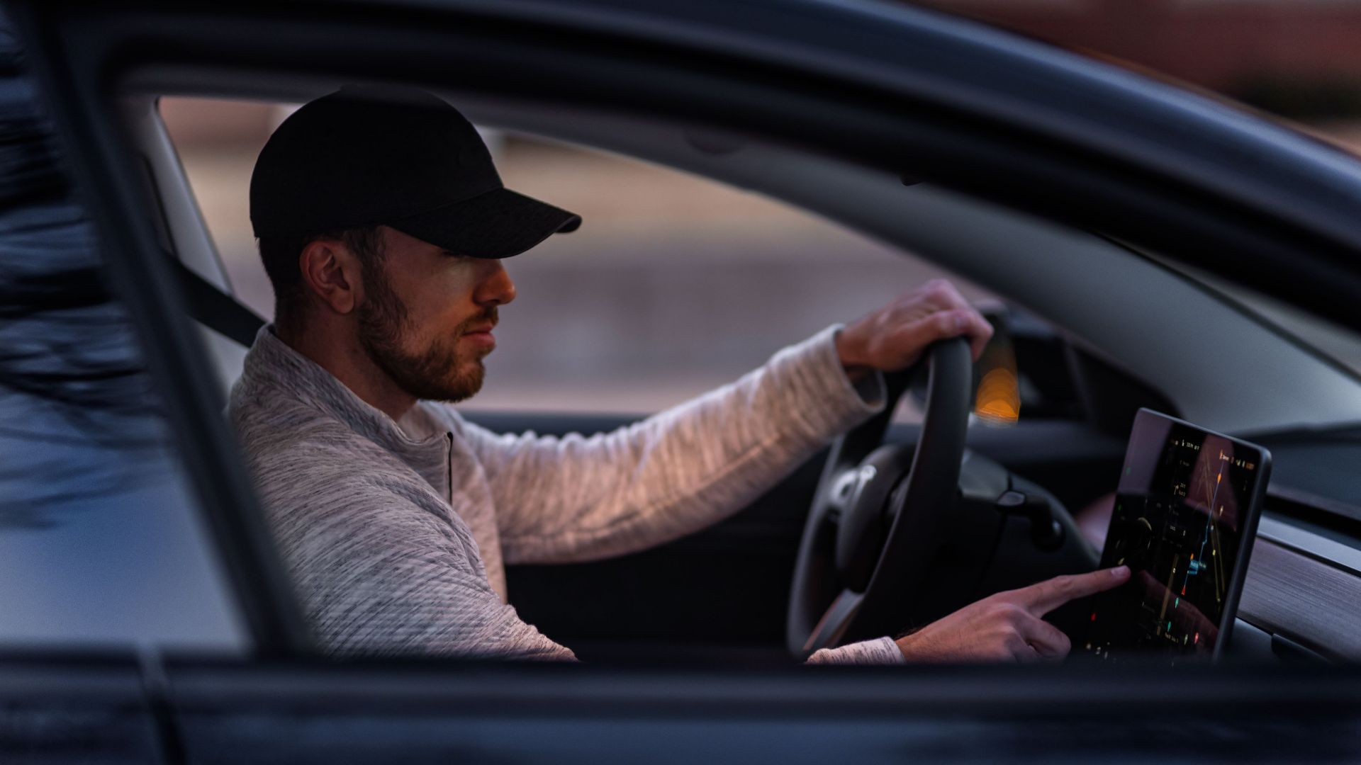 A man interacts with a touchscreen inside an electric car, driving through Dallas, TX.