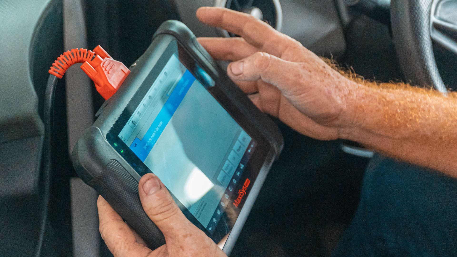 A mechanic uses a diagnostic tablet inside a car for vehicle analysis.