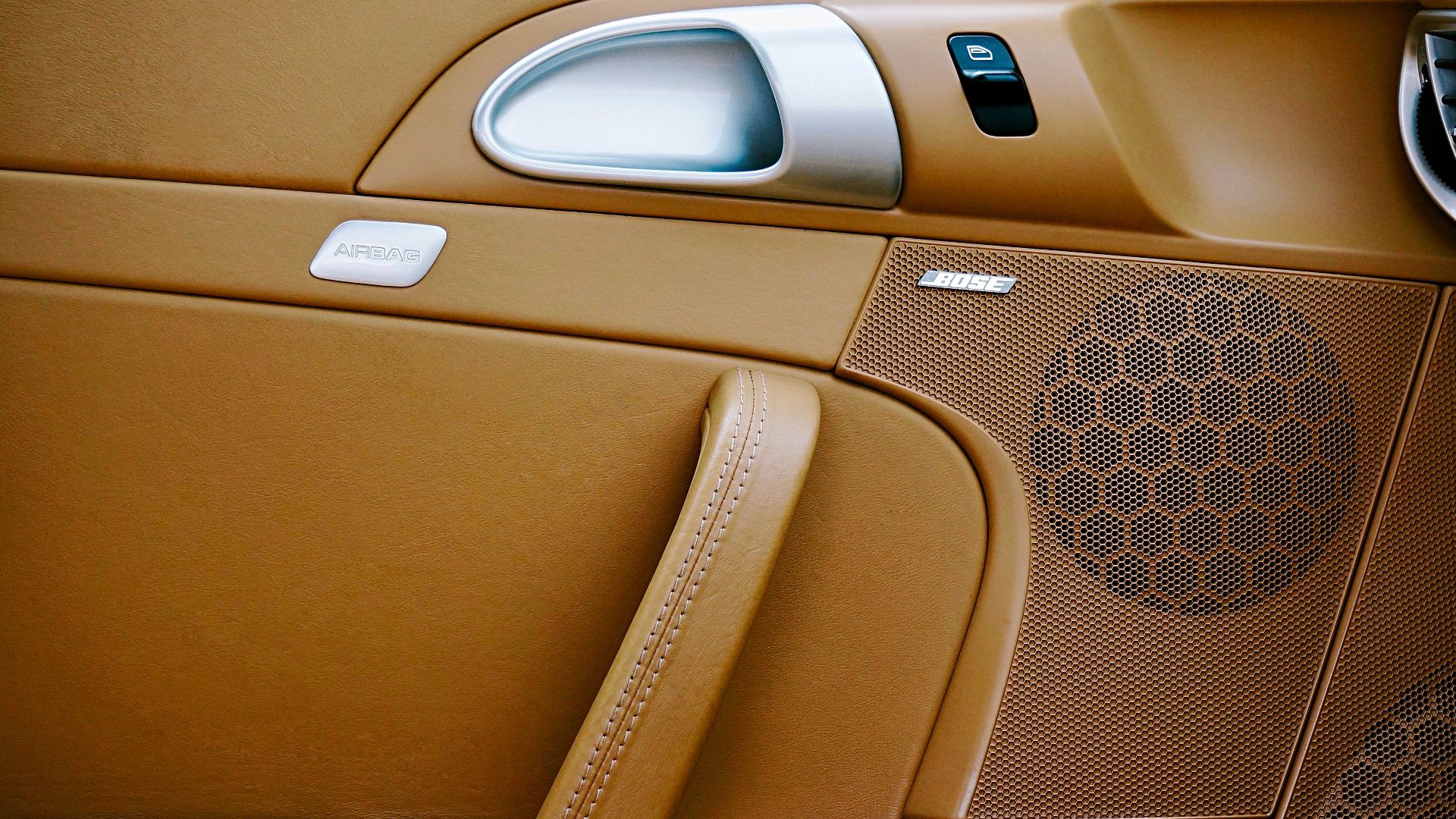 Close-up of a luxurious car interior featuring brown leather and a Bose speaker panel.