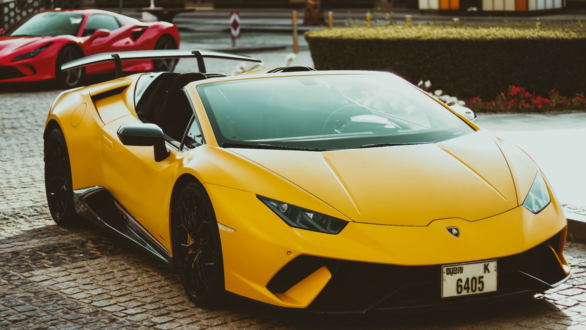 A striking yellow Lamborghini parked on a cobblestone street in Dubai, exuding luxury and style.