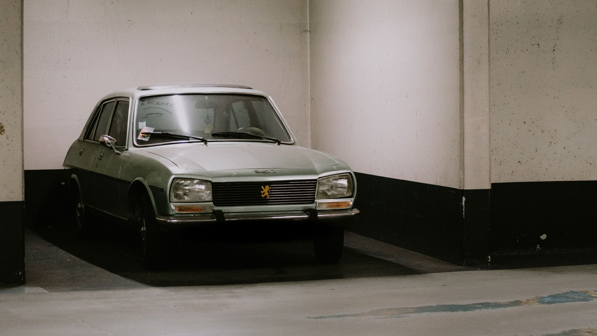 Classic vintage car parked in an underground garage with dim lighting creating a nostalgic atmosphere.