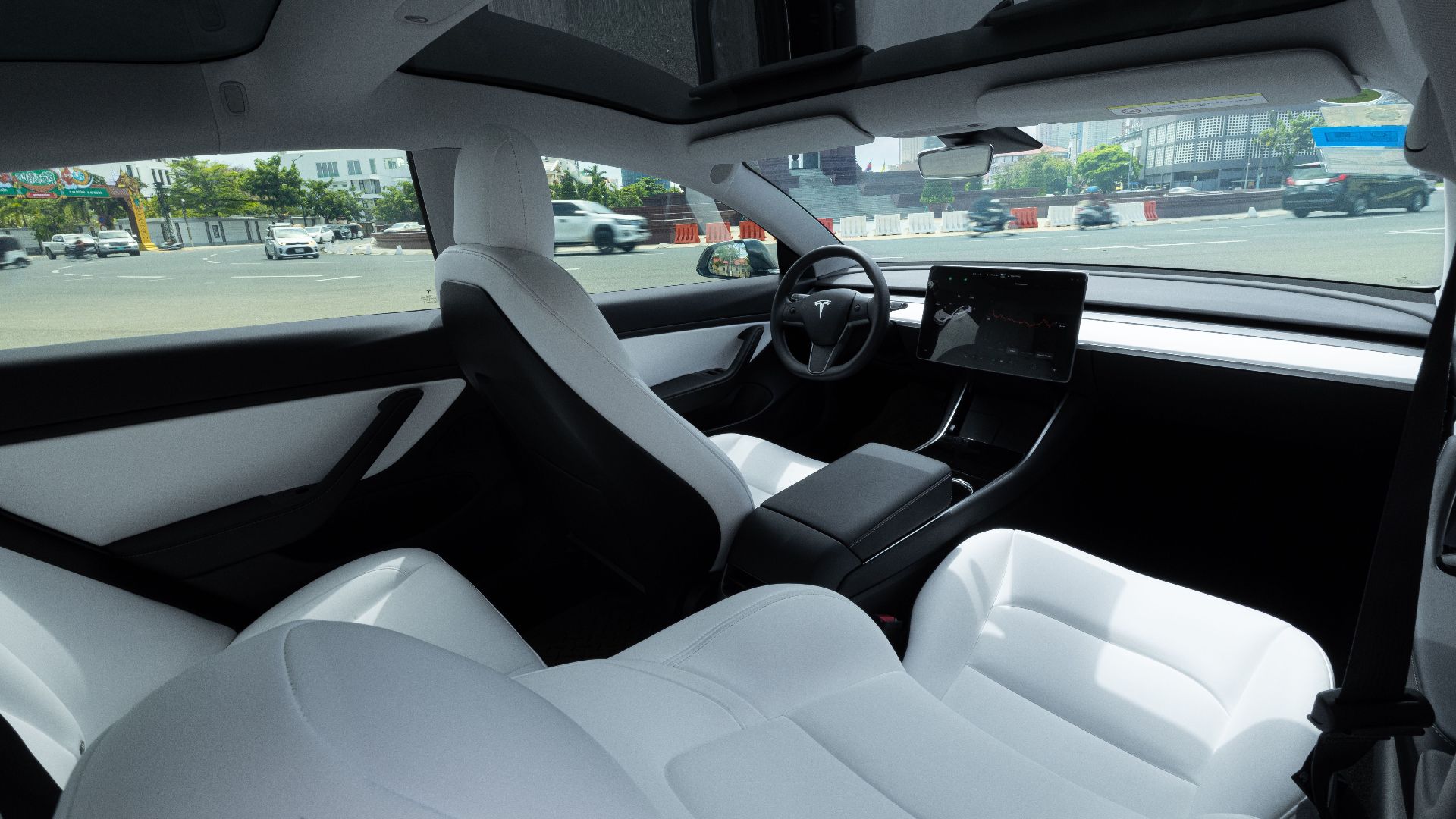 Elegant interior of an electric car featuring luxurious white leather seats and a panoramic view.