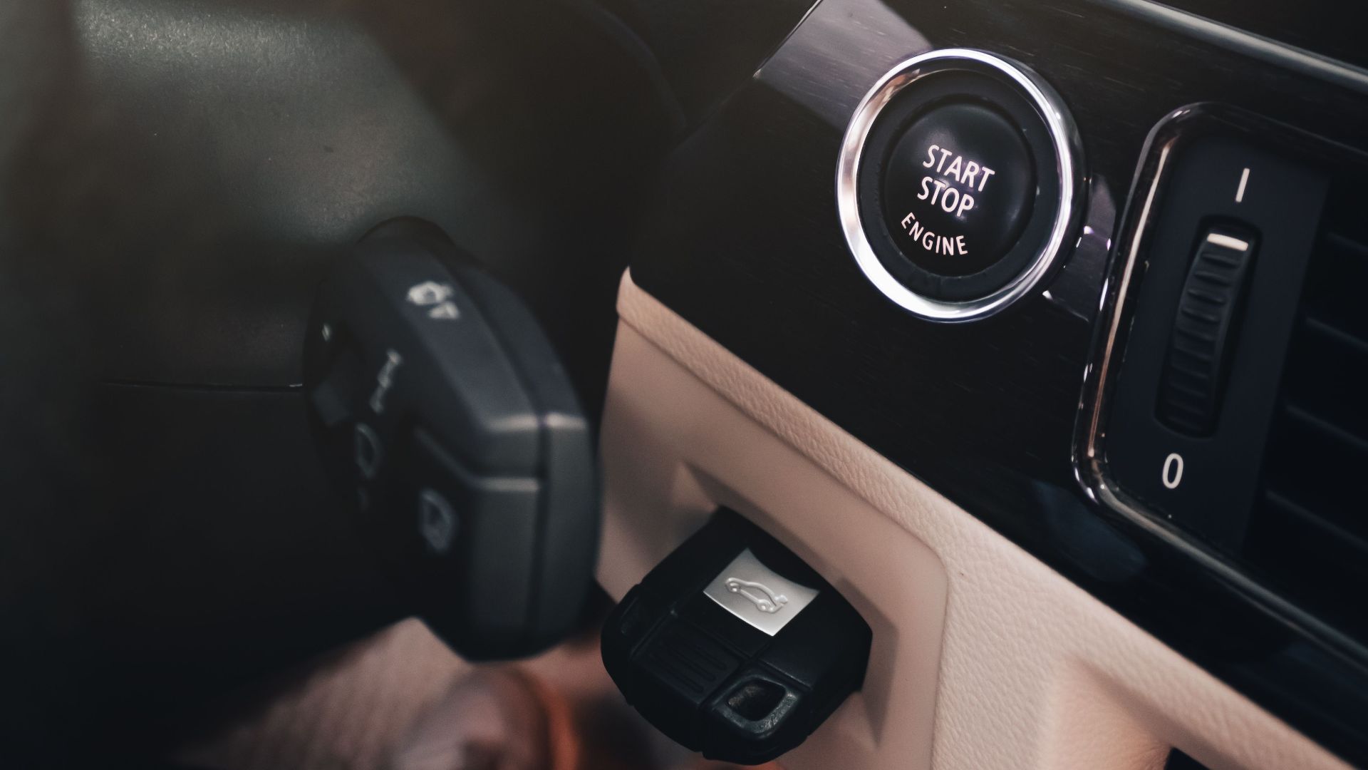 Close-up of a modern car's dashboard with illuminated gauges and start/stop button.