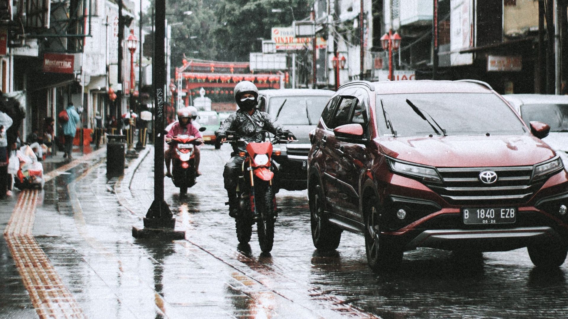 Traffic in West Java, Indonesia on a rainy day with cars and motorcycles.