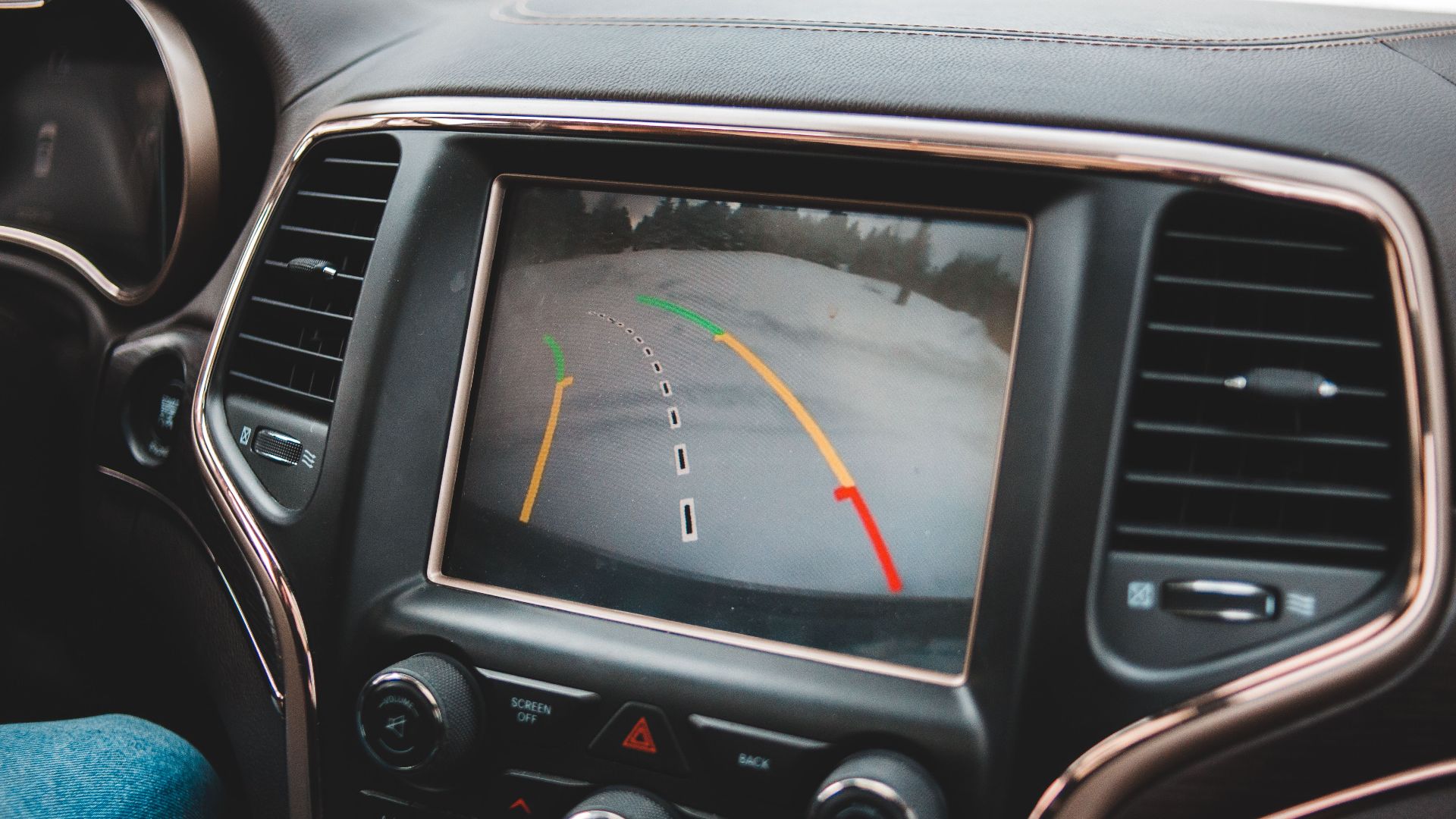 Close-up of a car's dashboard showing a rearview camera display for parking assistance.