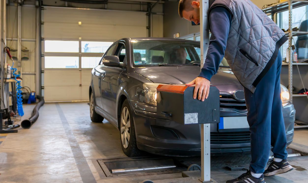 Inspector doing a checking of the headlights with a headlight tester.  Automobile car inspection headlight checkup at repair service station. Technical inspection of cars.