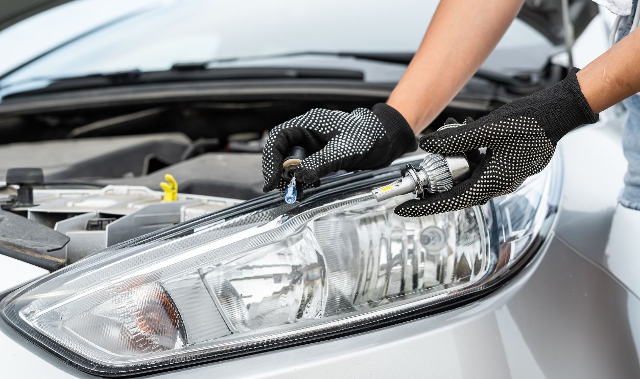 A man is fixing a car with change light bulb, repair lamp in passenger car headlight