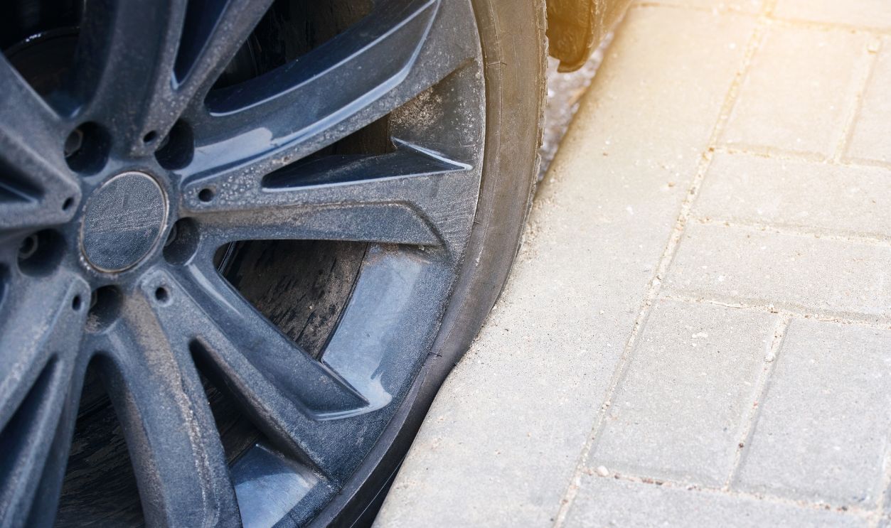 Car wheel parked close to the curb on parking lot. Tire touching the curb after parking, risk to damage sidewall of the low-profile tire