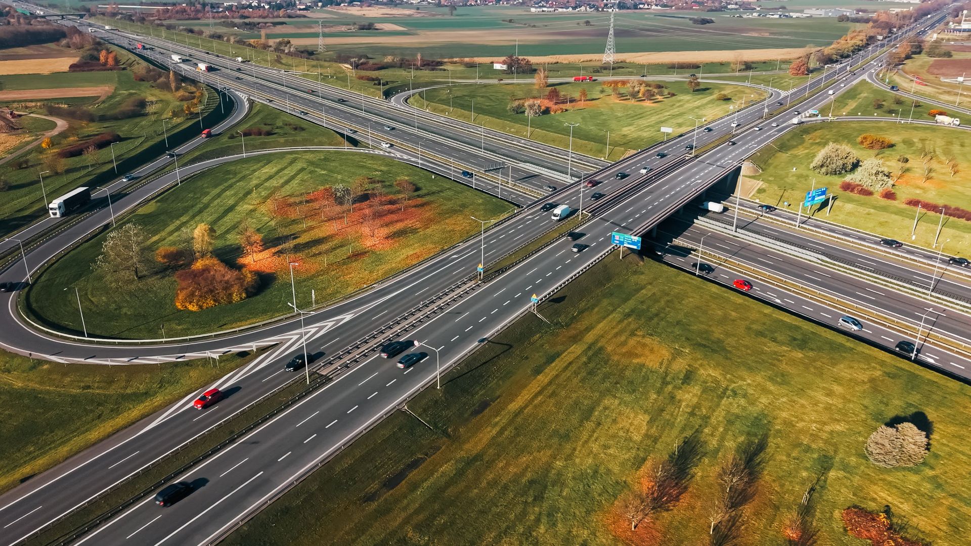 Aerial shot of a traffic-filled highway interchange surrounded by autumn foliage.