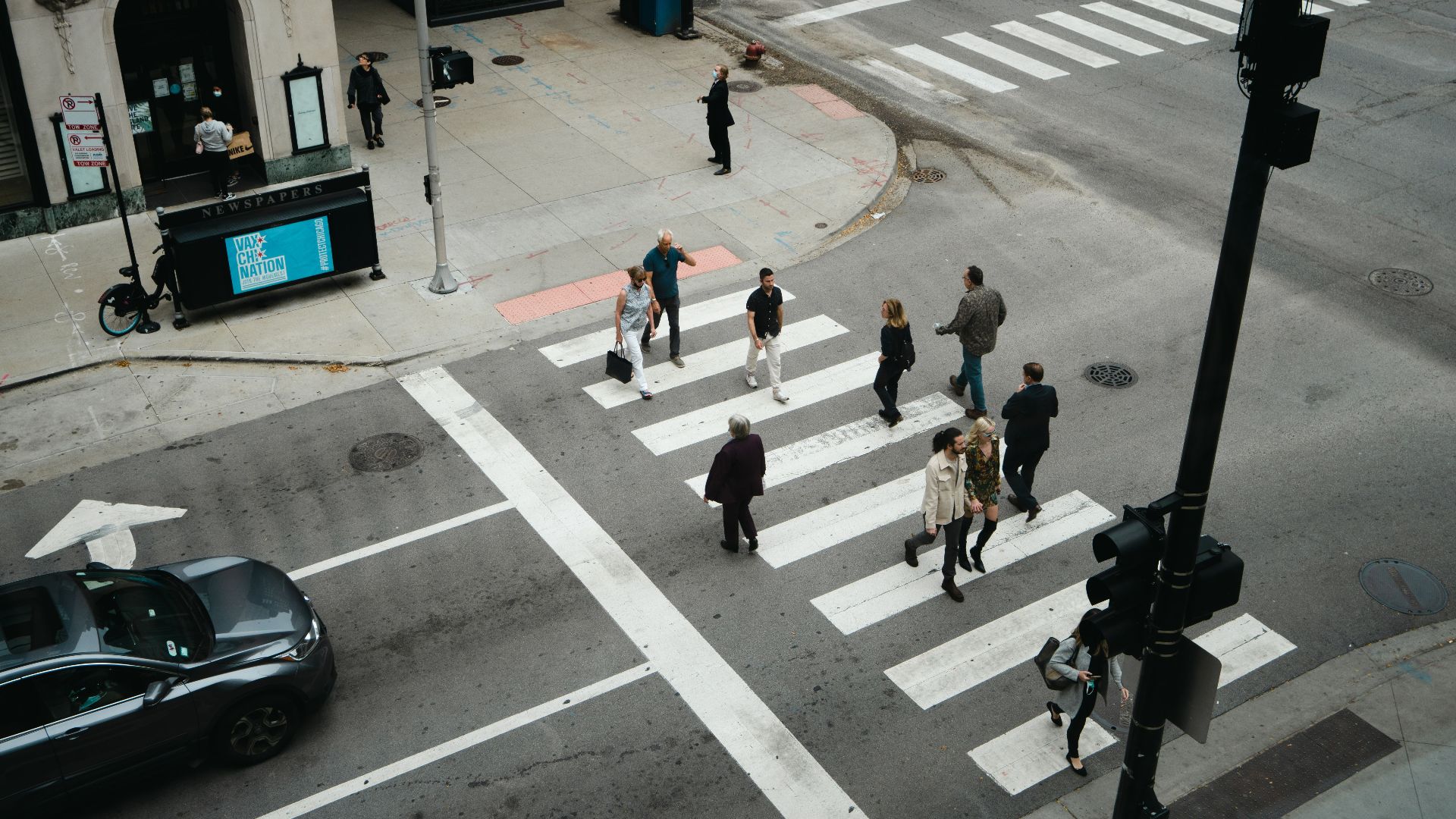 Aerial view of people crossing a city street at a pedestrian crosswalk.