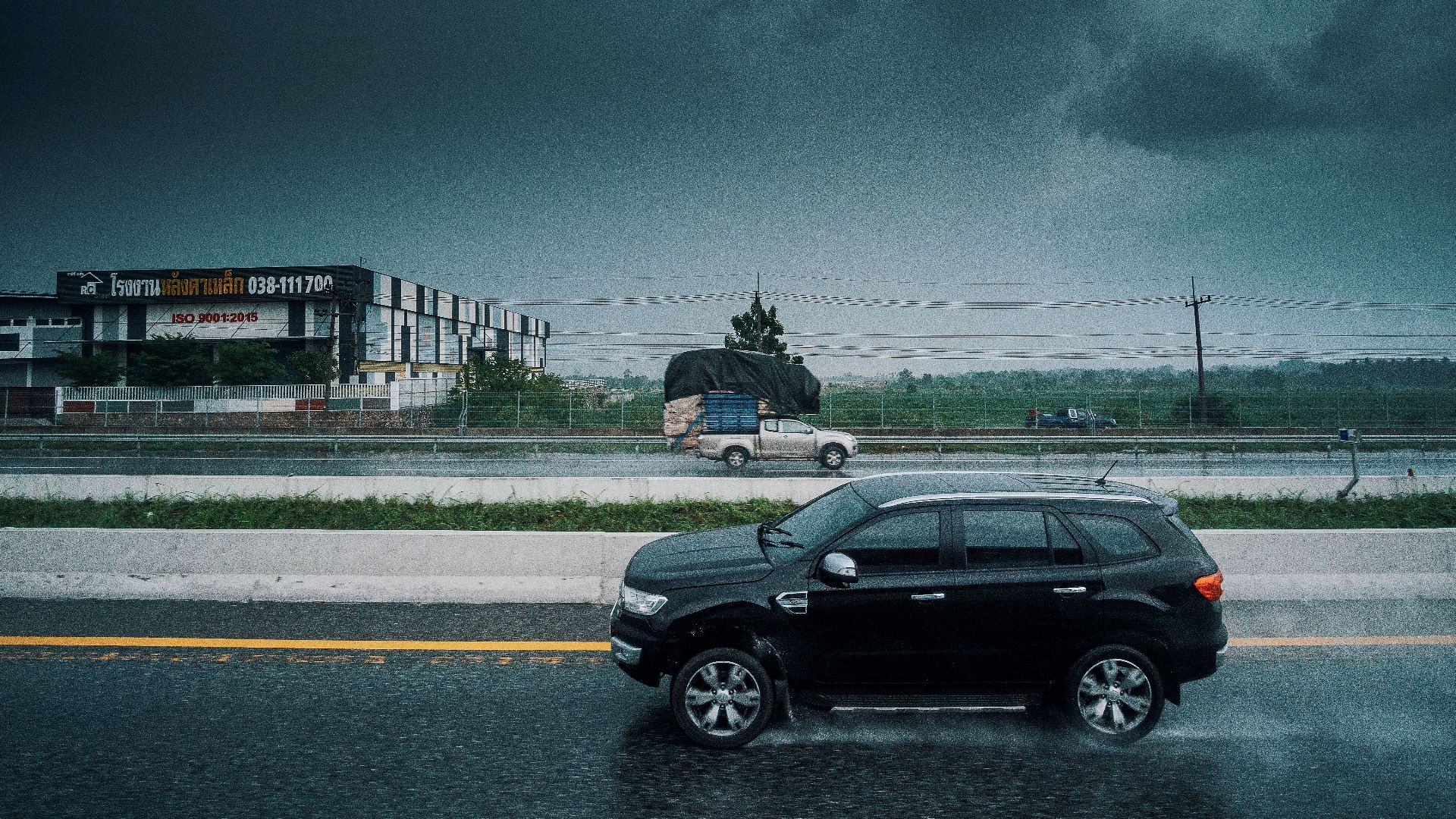 Black SUV travels on a rainy highway, showcasing stormy weather and transportation dynamics.