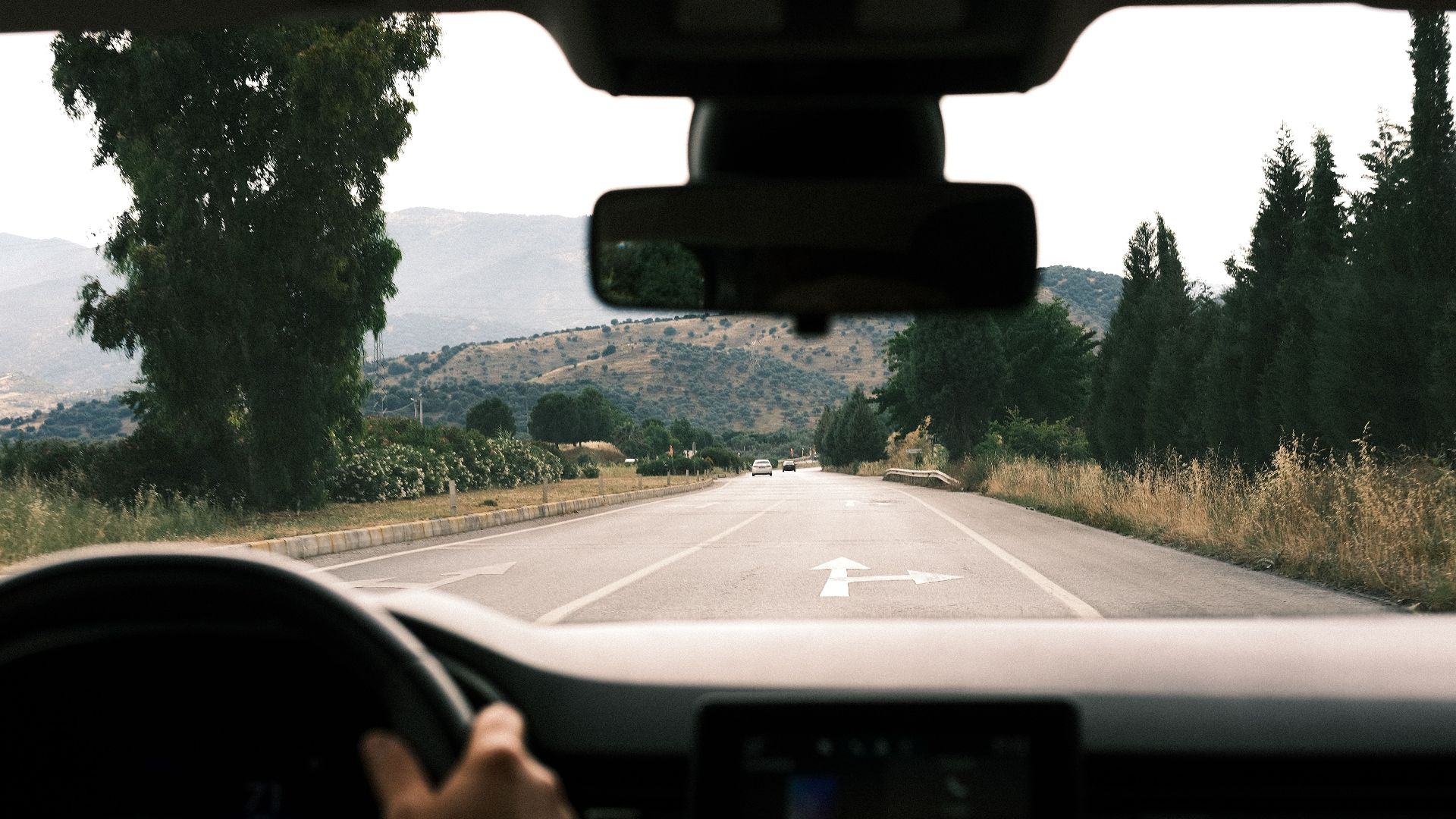 View from inside a car driving on a scenic, mountainous road during daytime.