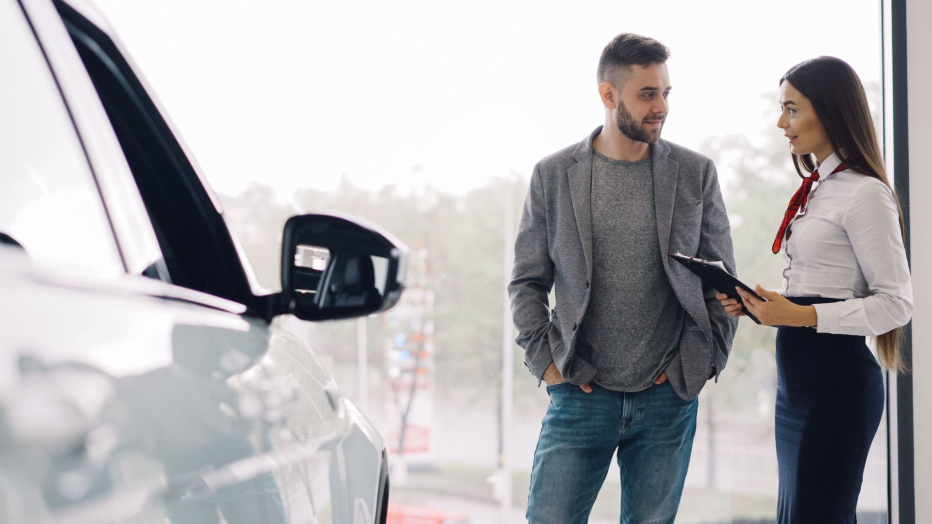 Man consulting with car salesperson in a showroom, discussing car options.