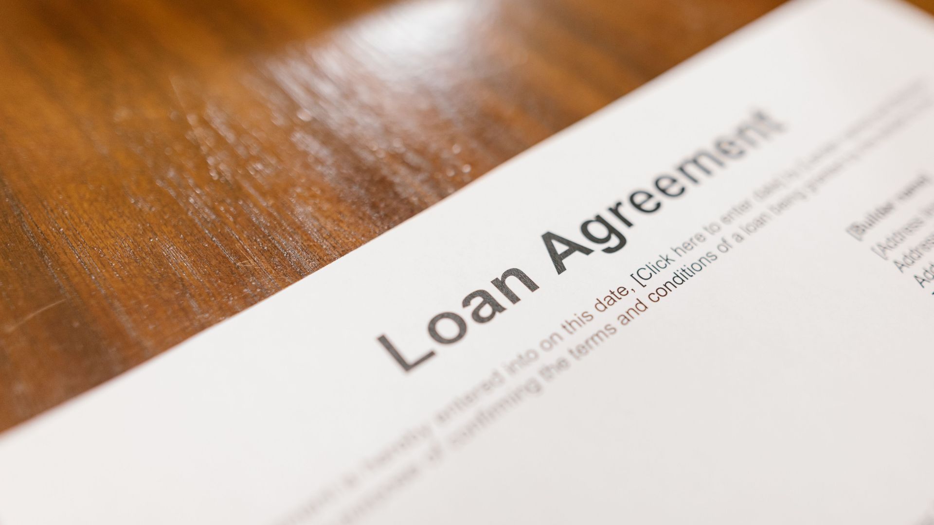 Detailed loan agreement document close-up on a wooden table representing legal and financial concepts.