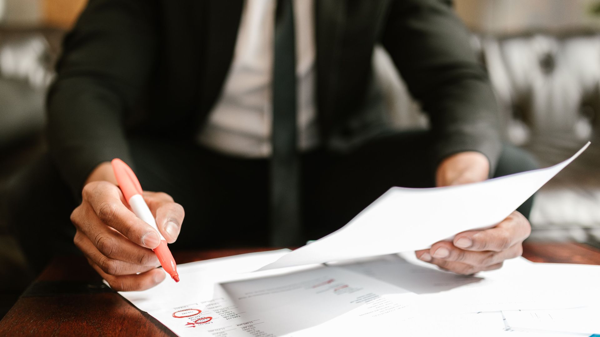 Businessman working with financial documents at office desk, highlighting details.