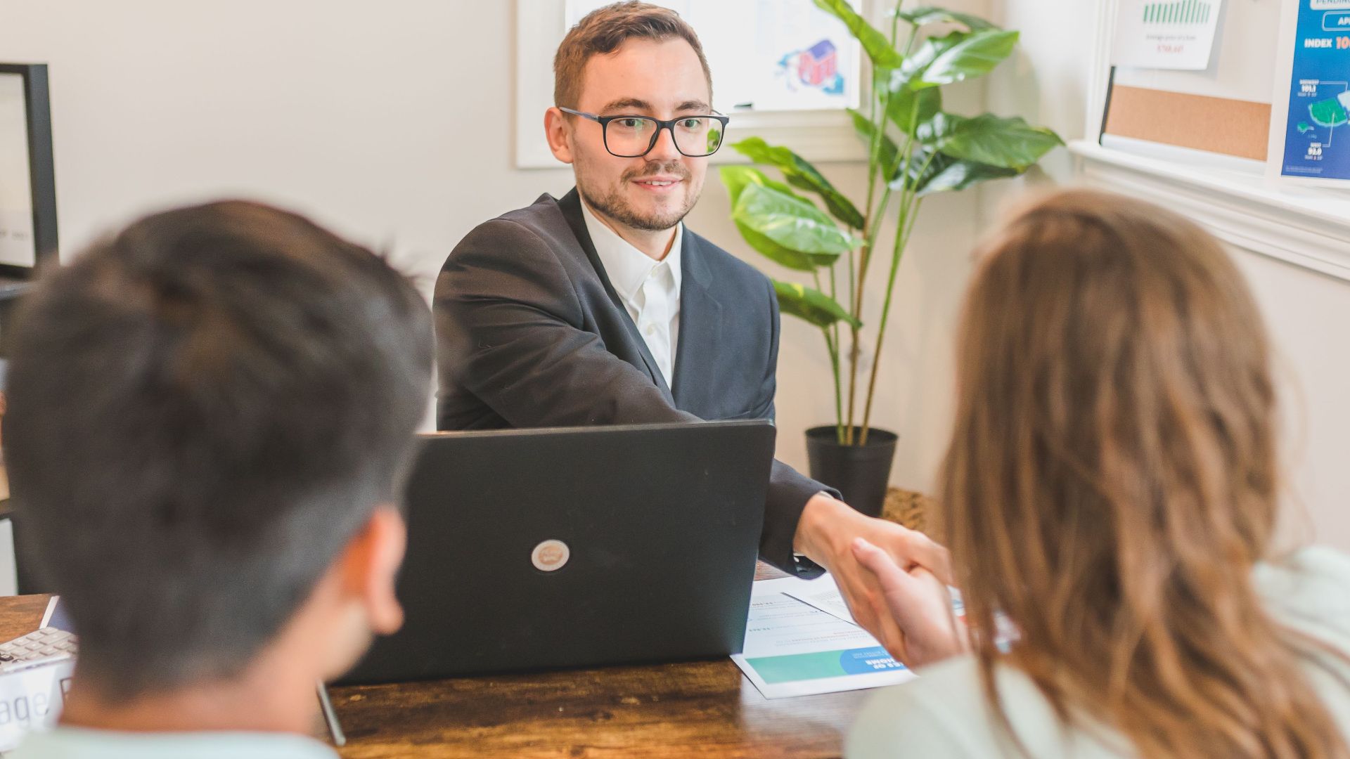 A mortgage broker meeting clients in an office, discussing agreements and loans.