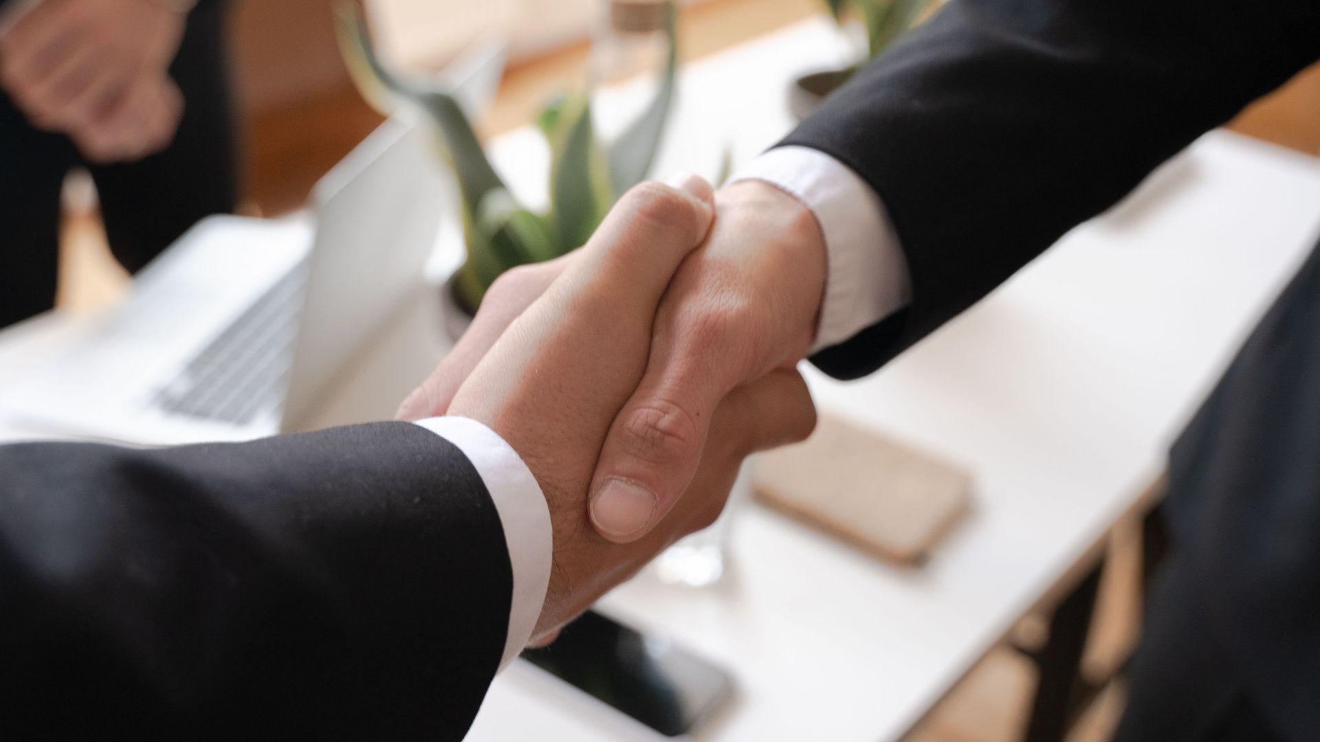 Close-up of a handshake between two professionals in a business setting, symbolizing agreement.
