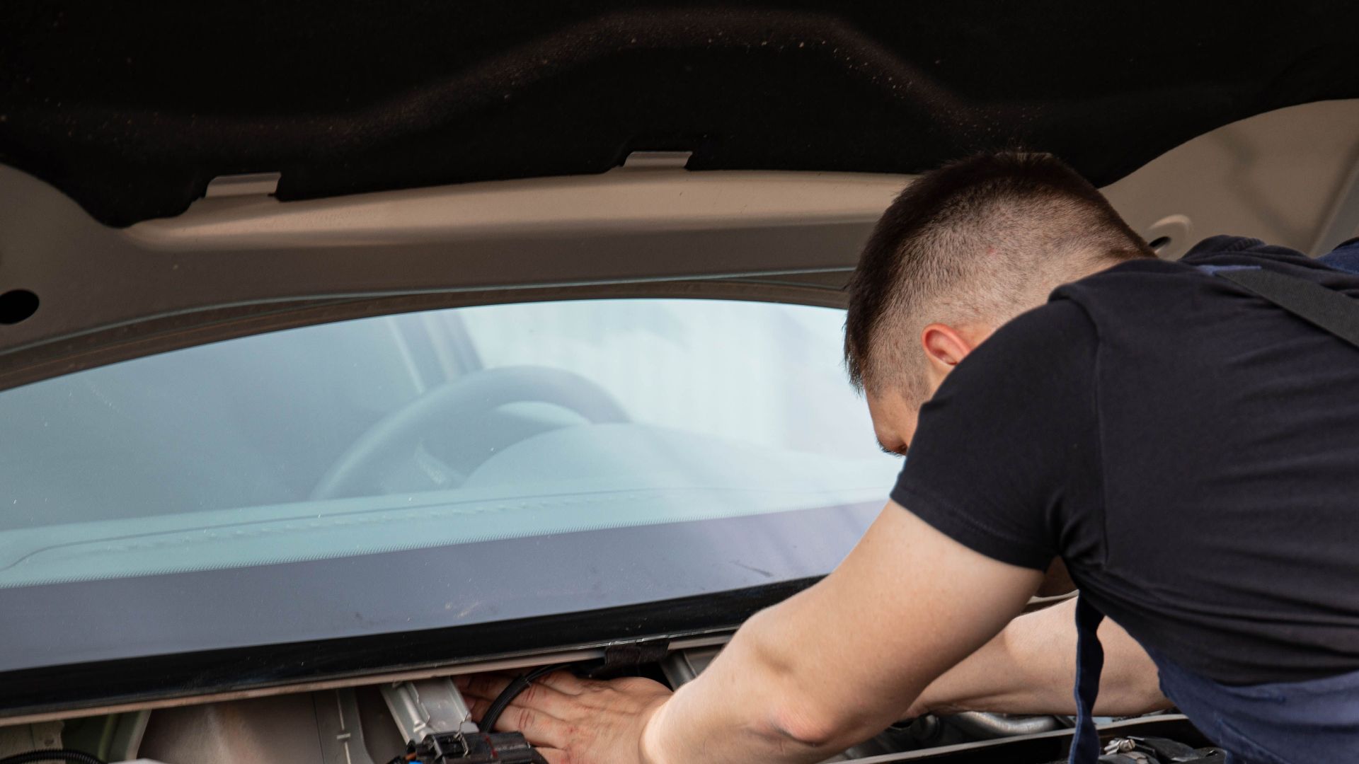 Auto mechanic performs engine maintenance on a car. Focus on hands and engine components.