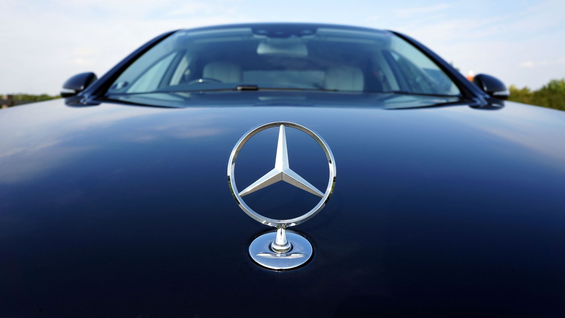 Close-up of a Mercedes-Benz emblem on a luxury car hood featuring a sleek design.