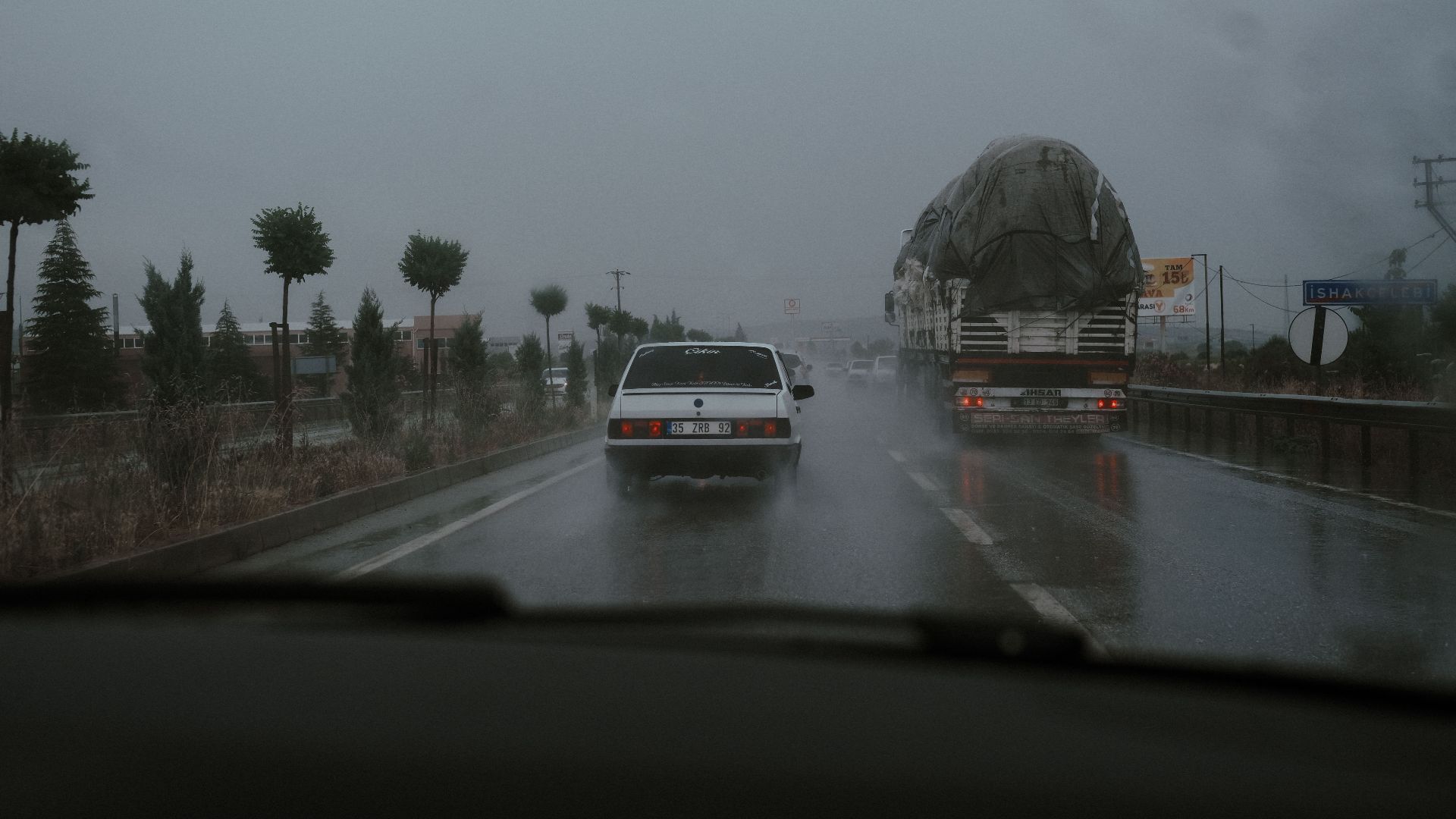 Vehicles driving on a wet highway during rainfall, showcasing road transportation challenges.