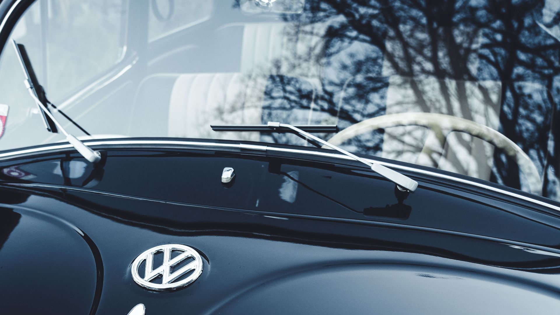 Close-up of a classic dark blue Volkswagen Beetle with the VW emblem. Captures the essence of vintage automotive design.