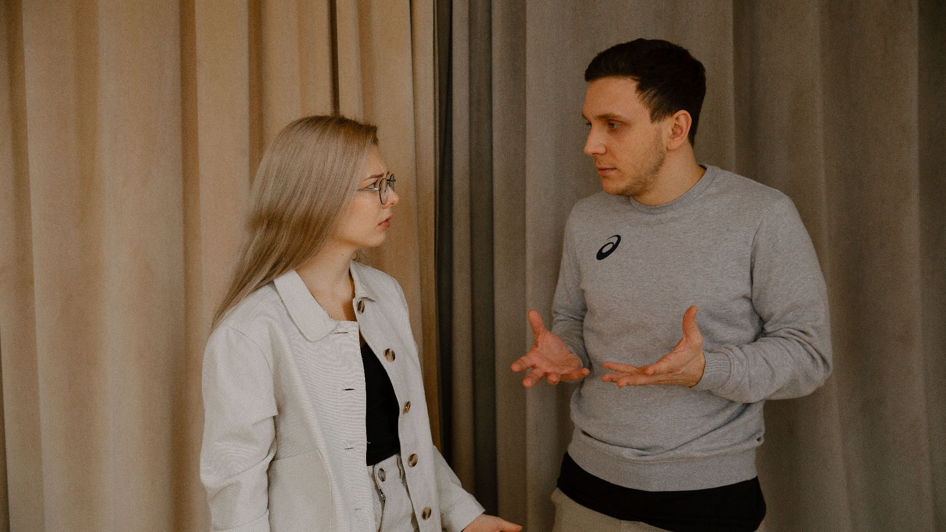 A young couple passionately discussing indoors, capturing intense emotions and gestures.