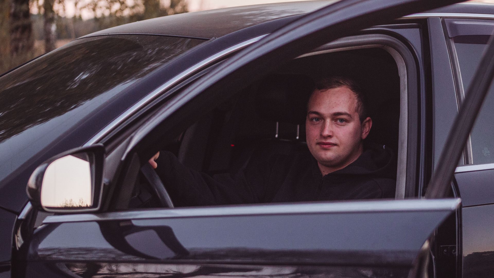Male driver in a parked car during twilight, capturing a serene moment.