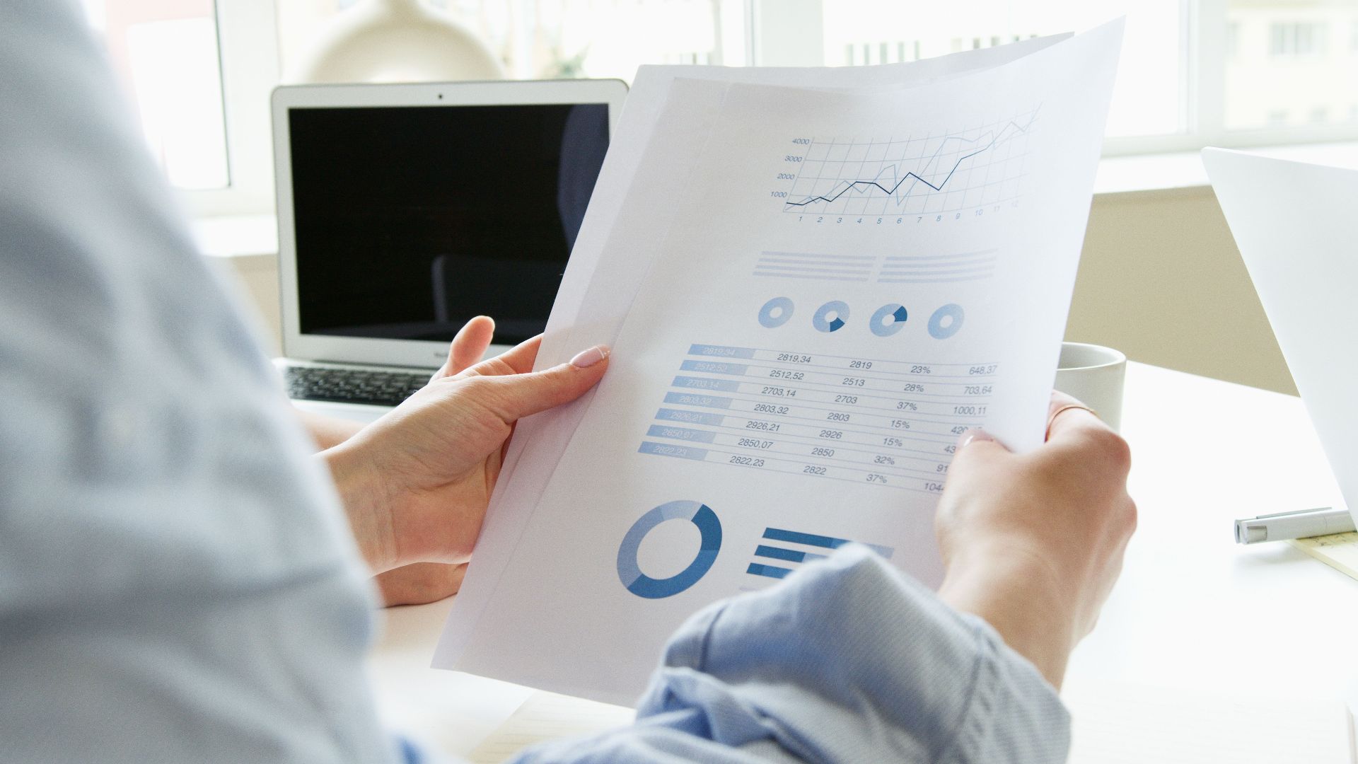 Close-up of a person analyzing business charts and graphs indoors.