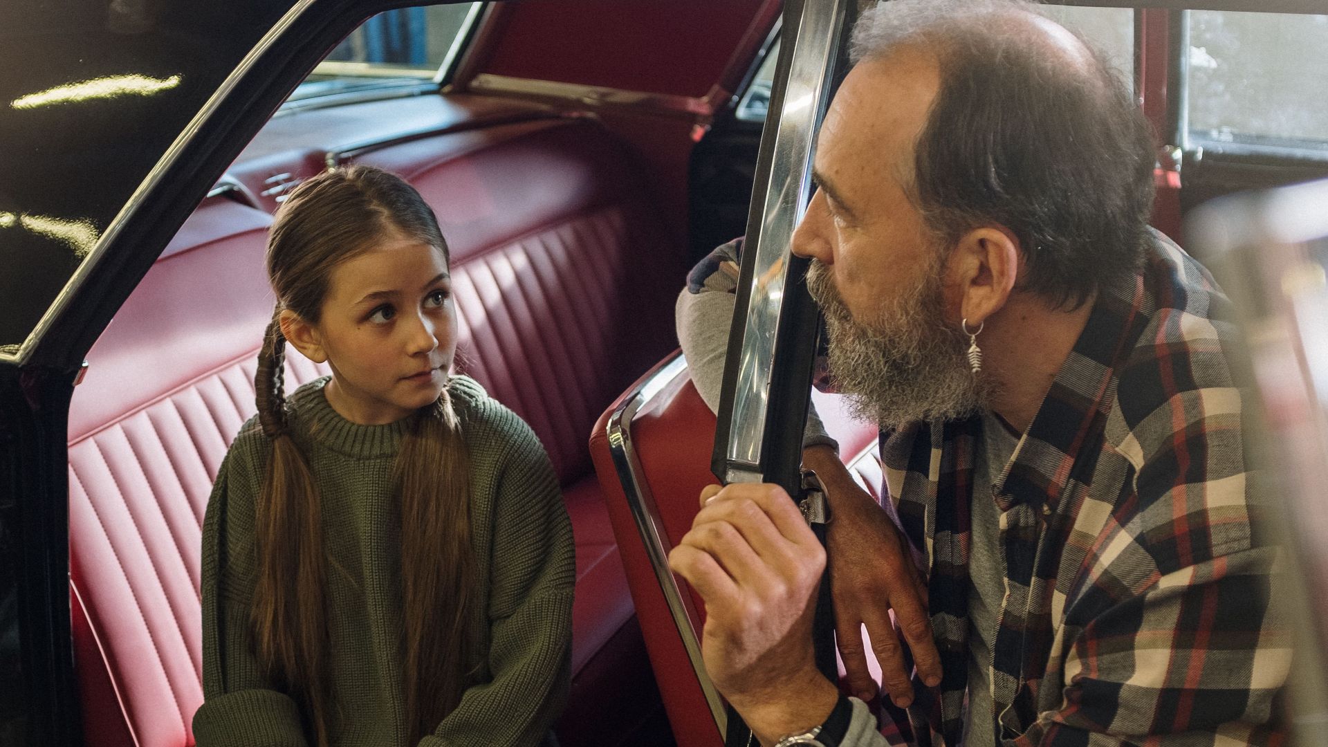 Father and young daughter share a moment inside a vintage car, highlighting family togetherness and nostalgia.