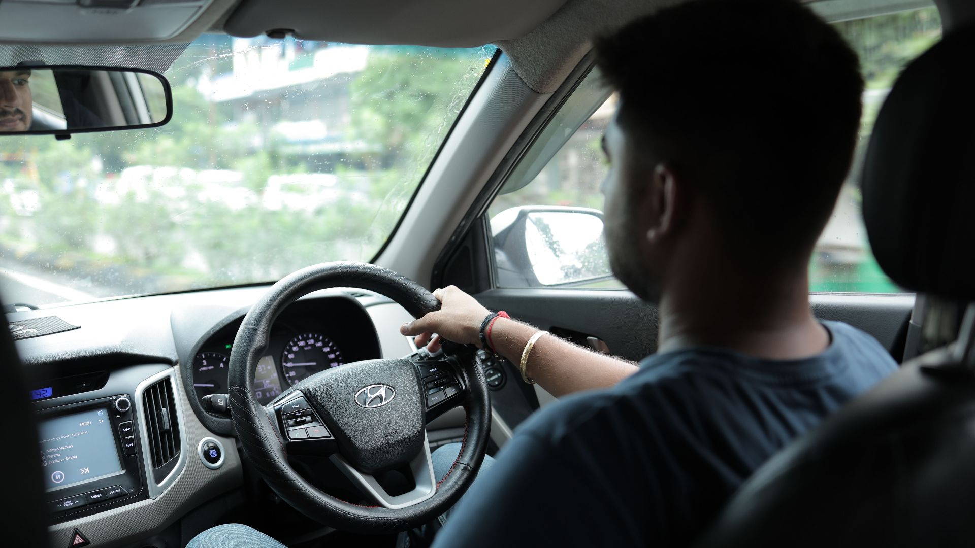 View from the passenger seat showing a man driving, focusing on the car's interior and road ahead.