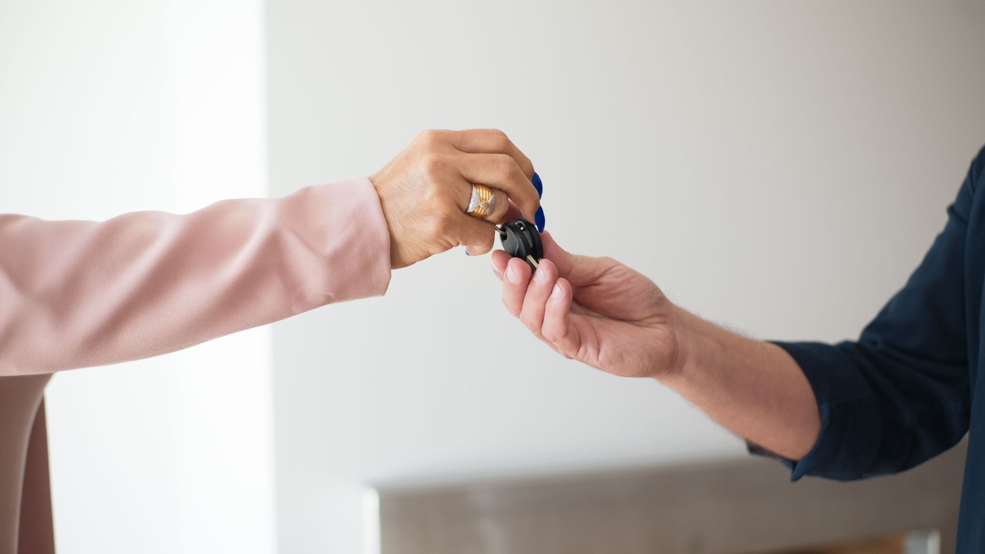 A close-up photo depicting the exchange of keys between two adults, symbolizing a real estate transaction.