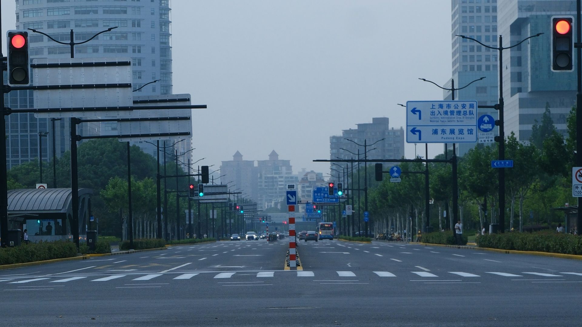 An empty city street with tall buildings and traffic lights.