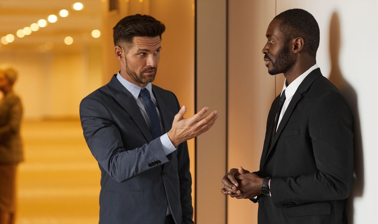 Two businessmen in formal attire engaged in a serious discussion in a modern office