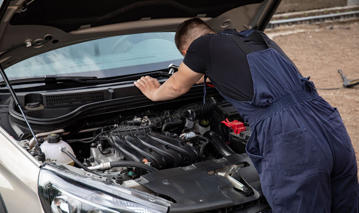 Mechanic checking car engine outdoors, focusing on vehicle maintenance