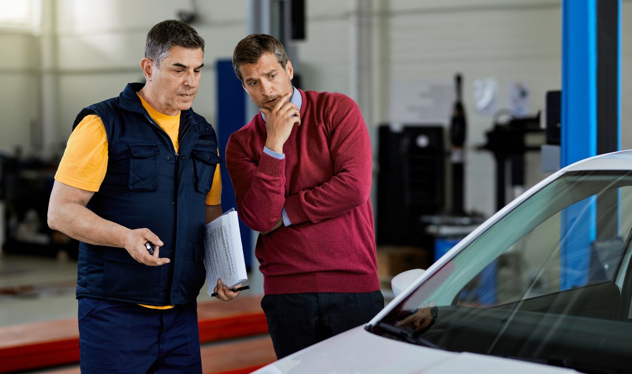 Shutterstock-1766946866, Worried customer talking with car mechanic in auto repair shop.
