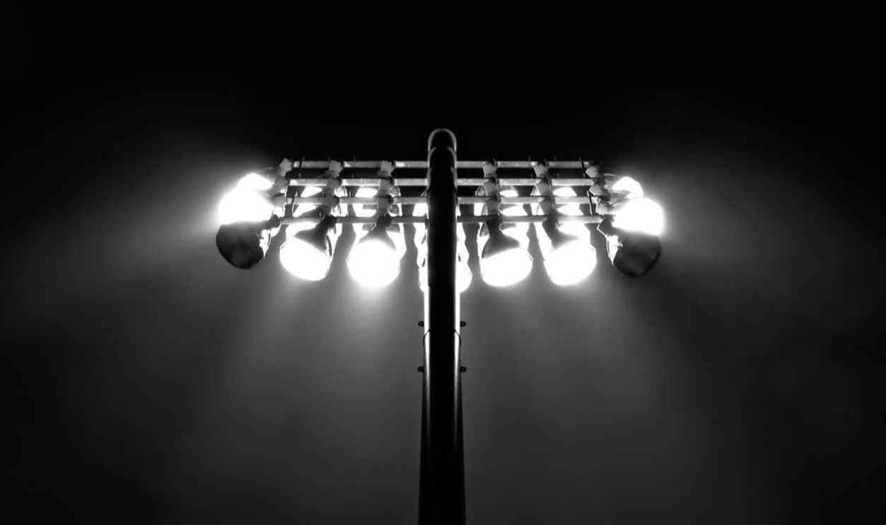 Black and white photo of stadium floodlights illuminating the night sky in Boston