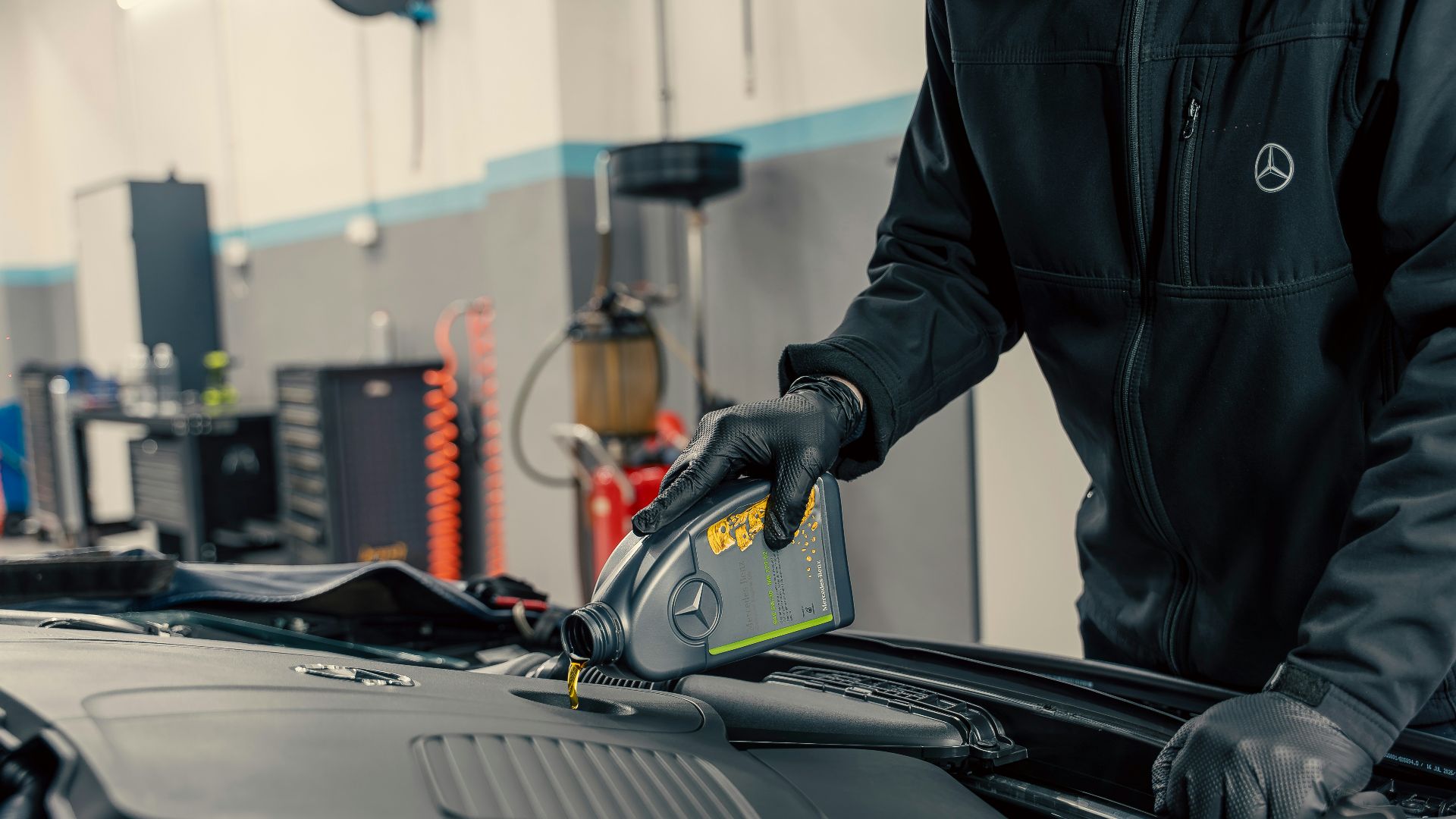 Mechanic pouring oil into car engine