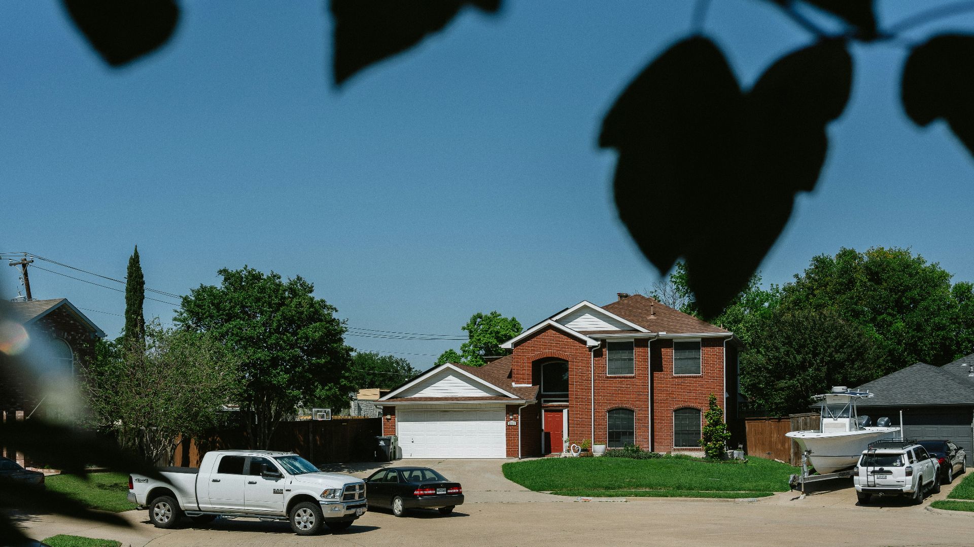 Brick house with cars in the driveway.