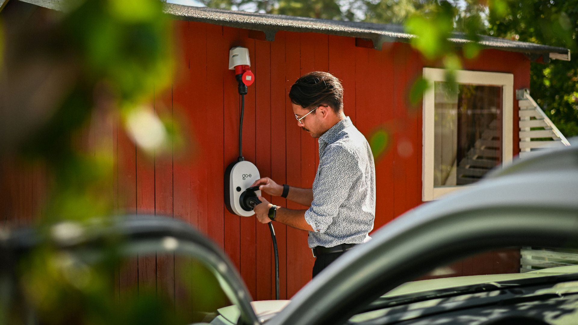 Man plugging in an electric car charger.