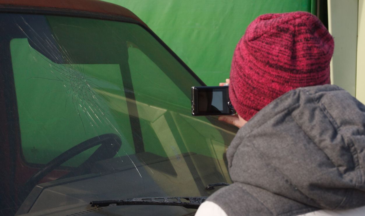 Young woman car insurance agent taking a picture of wrecked car to calculate the damage on a claim form