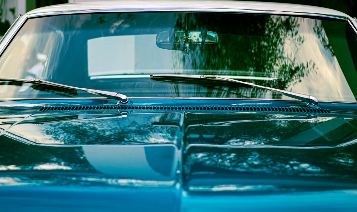 A close-up view of a classic blue vintage car windshield with reflections