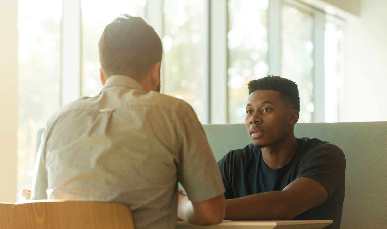 Two men sitting at a table in a modern office space during the day