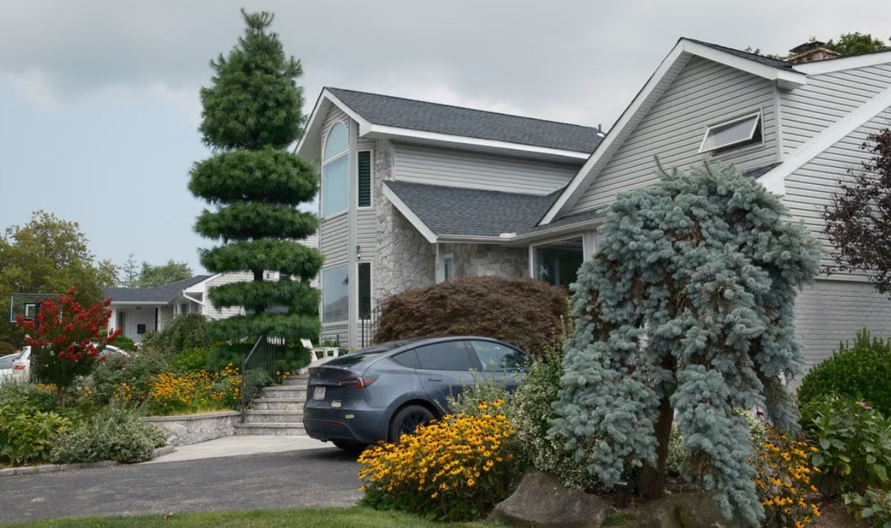 Elegant suburban house with diverse landscaping includes car in driveway