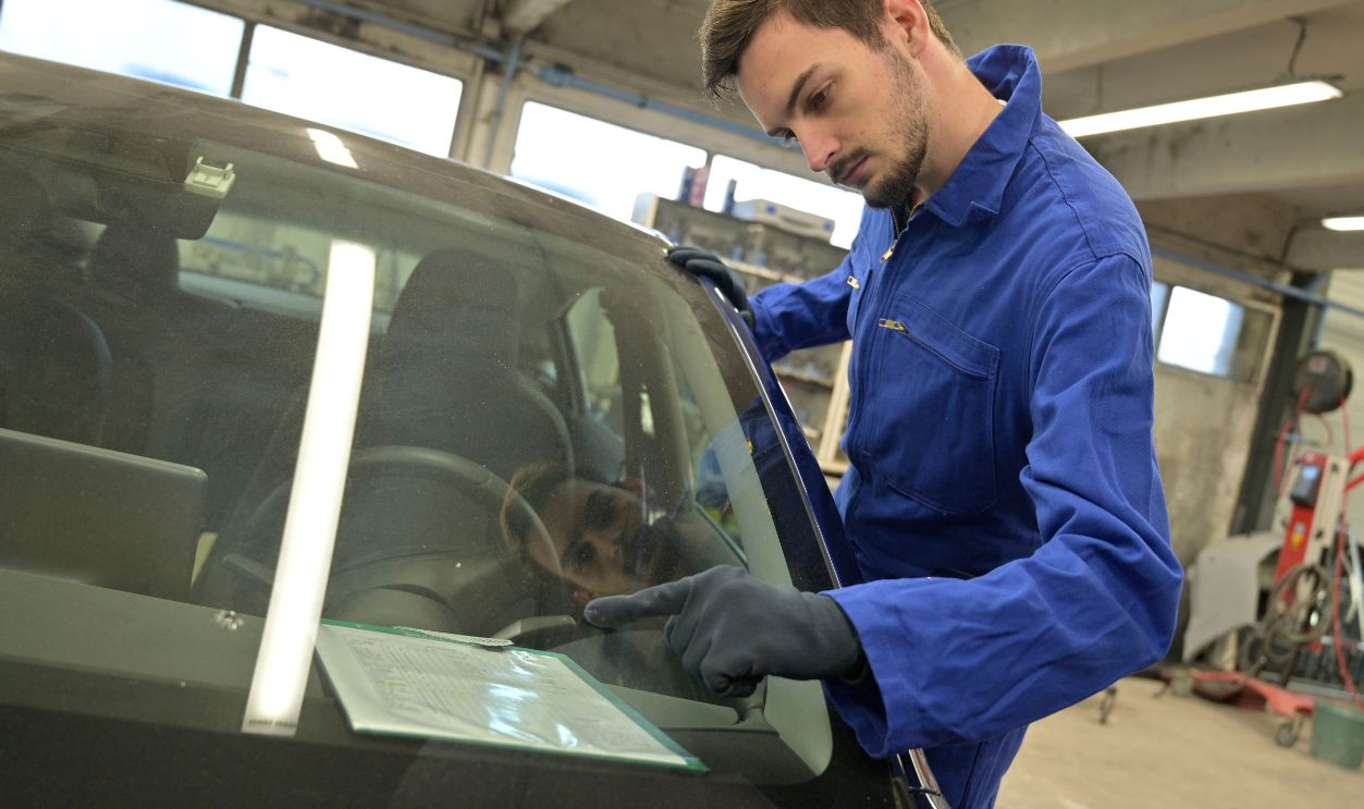 Apprentice working on car engine in workshop