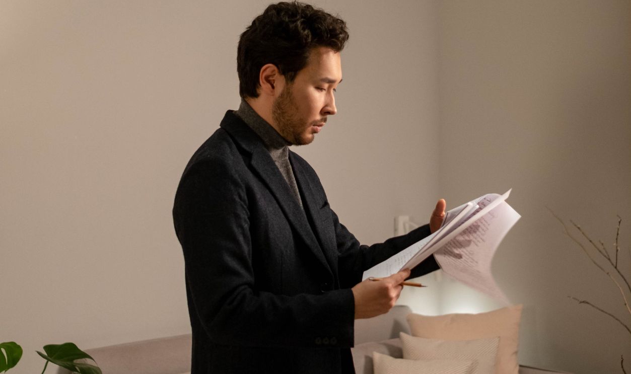 Stylish man in elegant setting reading papers indoors, showcasing a modern lifestyle